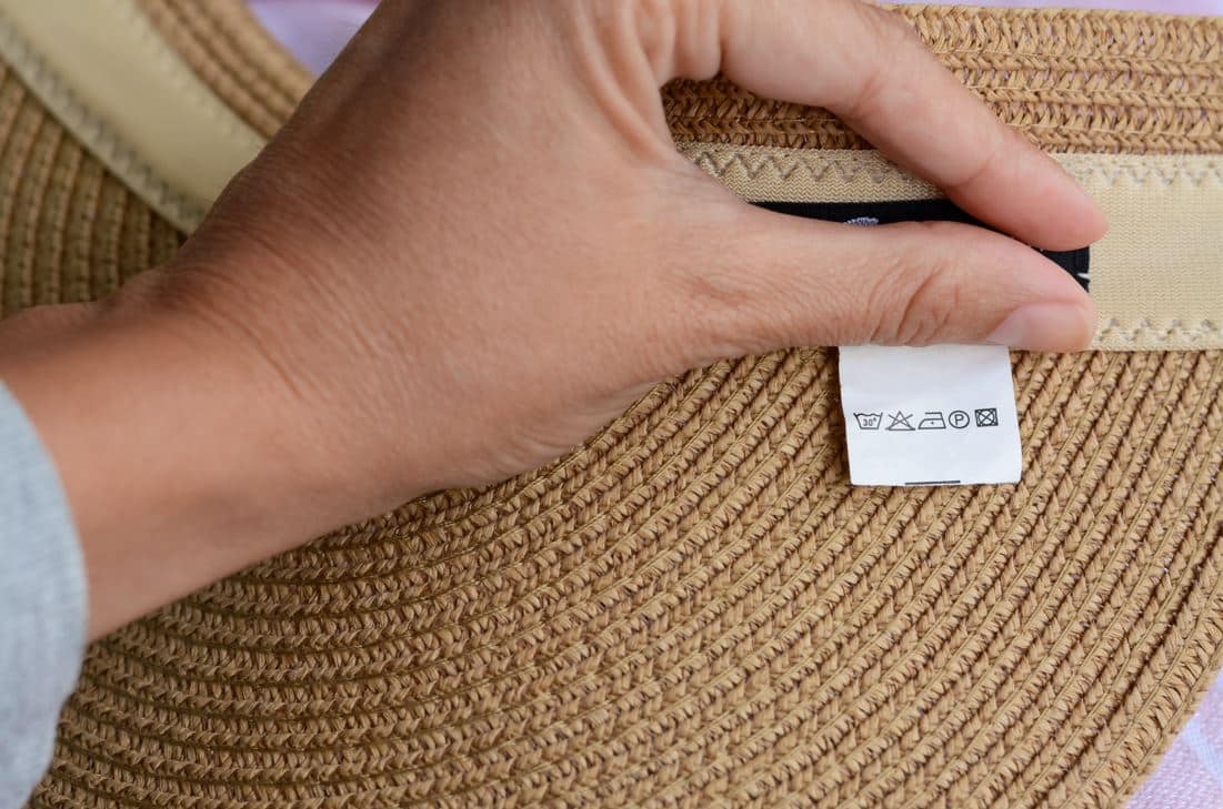 person showing safe wash instructions that are on a large straw hat
