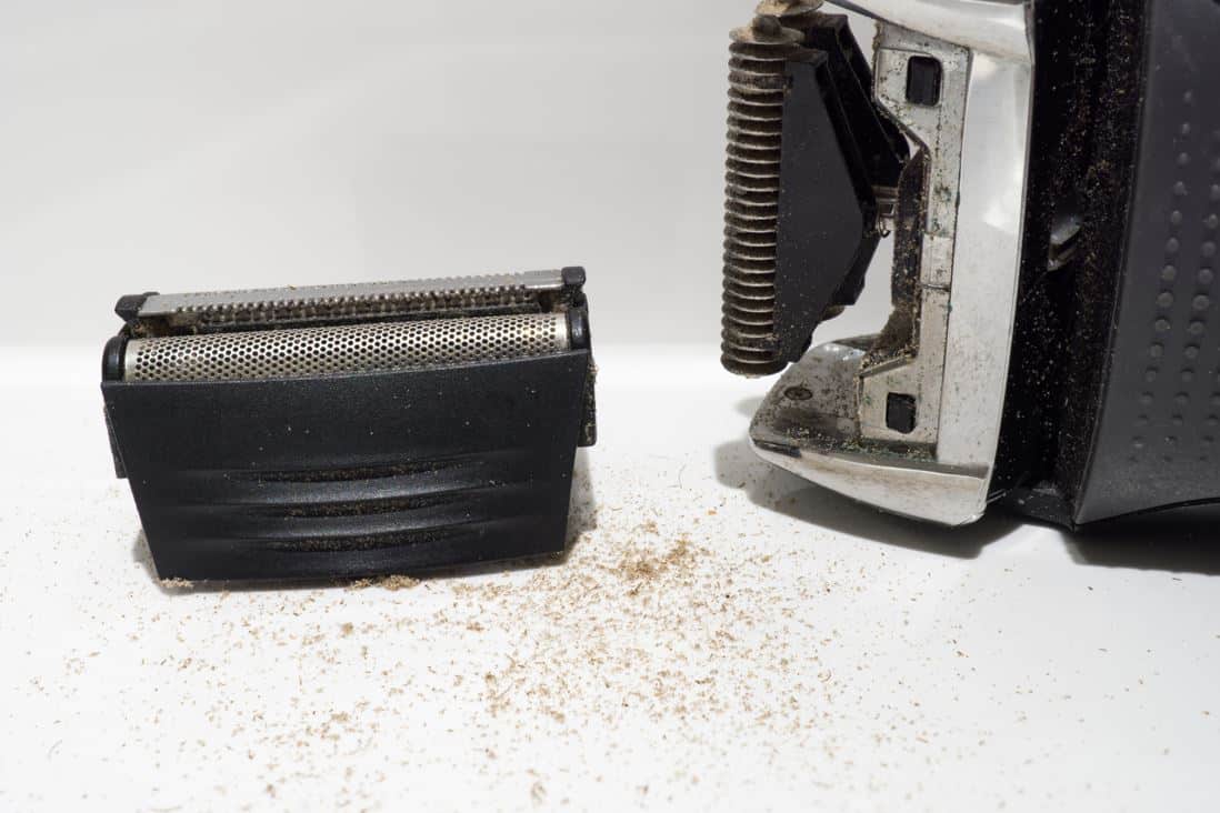 dirty electric shaver disassembled on a white countertop
