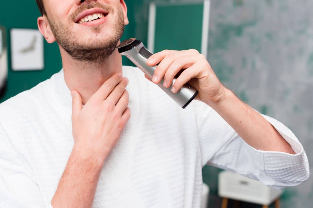 man using a chrome handheld shaver to shave neck stubble