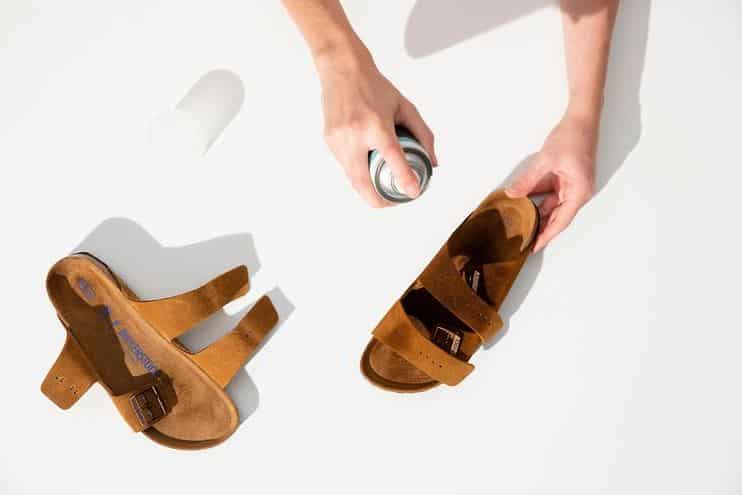 person using protective spray on fabric based birkenstock