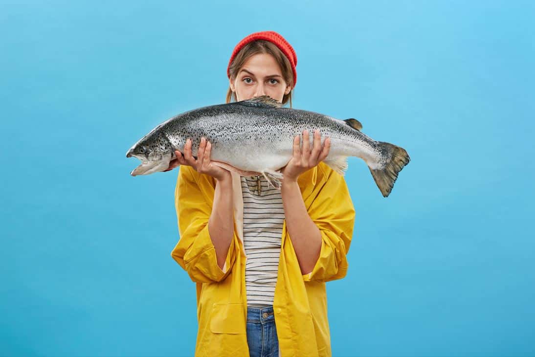 woman wearing yellow jacket holding large fish