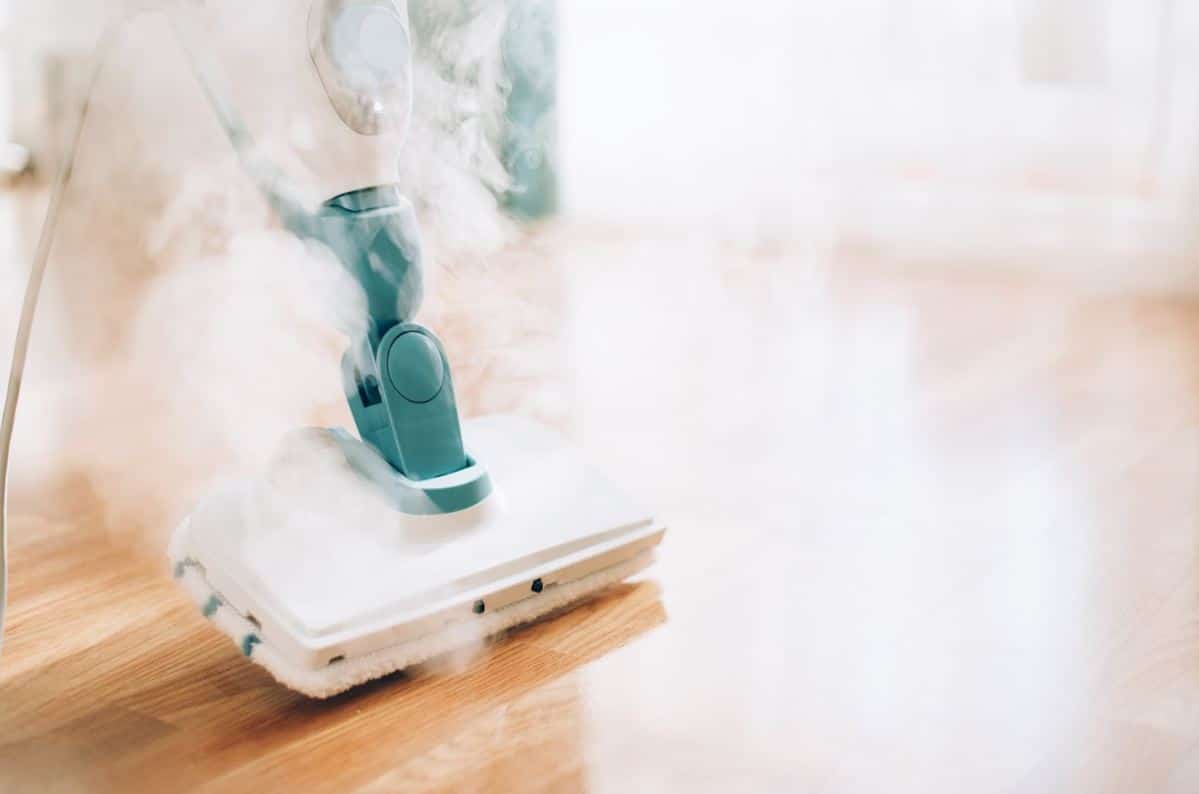 white and green steam mop being used on a wooden floor