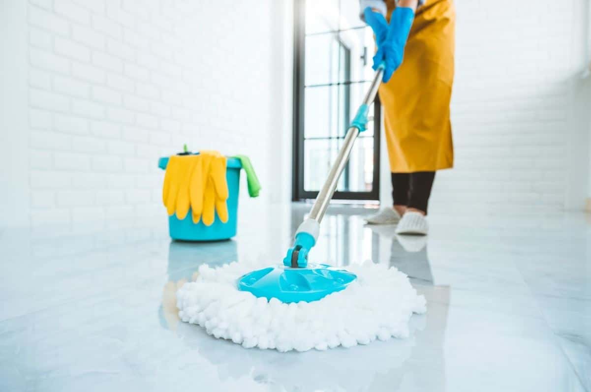 woman using wet mop to mop large bathroom