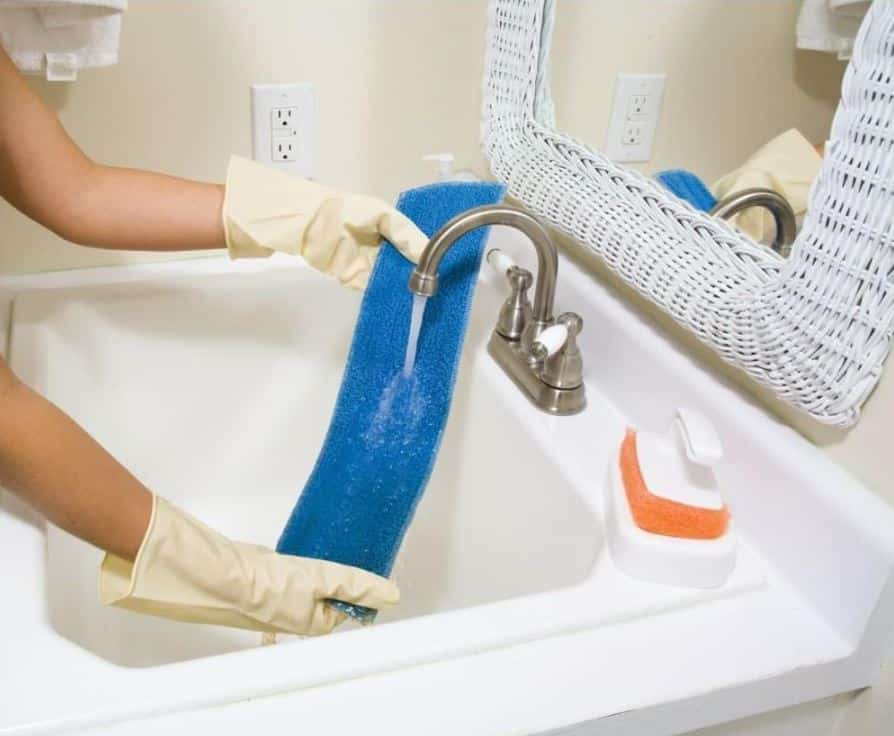woman washing blue mop pad in porcelain bathroom sink