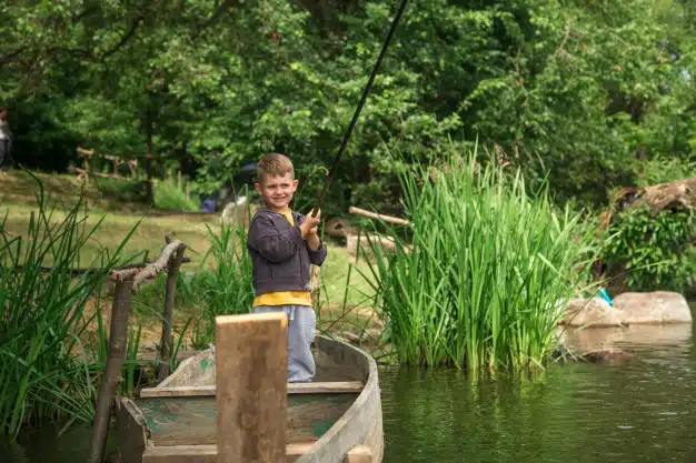 Boy with fishing rod fishing wooden boat