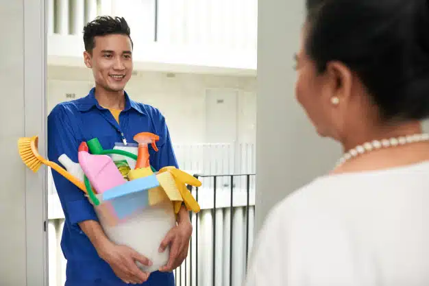 cheerful-asian-janitor-with-tools-standing-door-talking-with-wealthy-female-homeowner