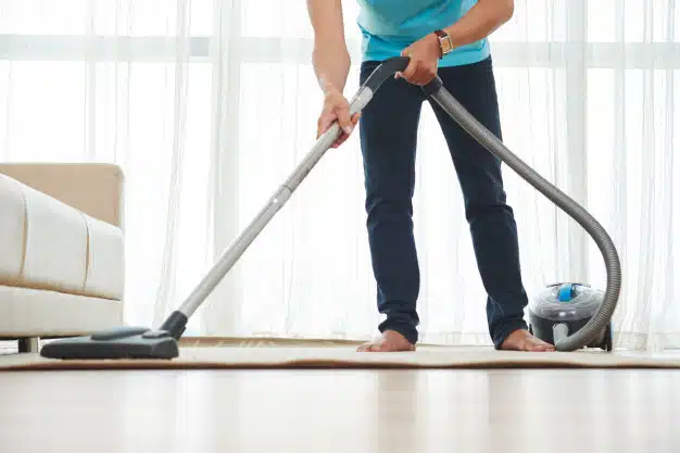 lower-body-shot-unrecognizable-man-vacuuming-carpet-home