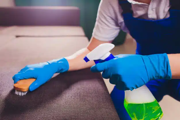 male-hand-light-blue-protective-gloves-cleaning-sofa-couch-room