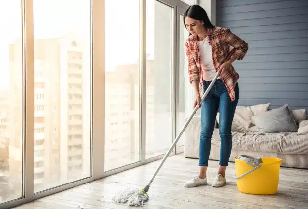 Woman smiling while cleaning floor