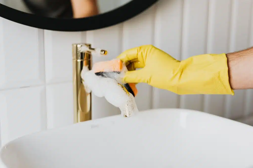 Man washing faucet in bathroom with soapy water