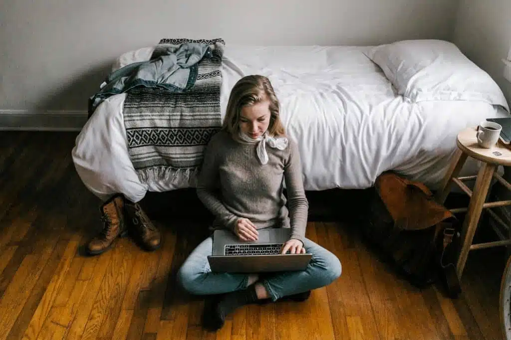 Woman in gray sweater sitting on hardwood floors