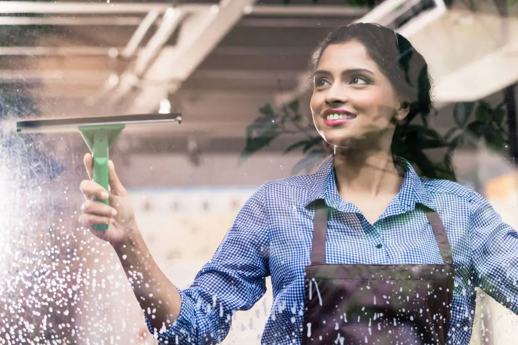 employee cleaning windows with a squeegee