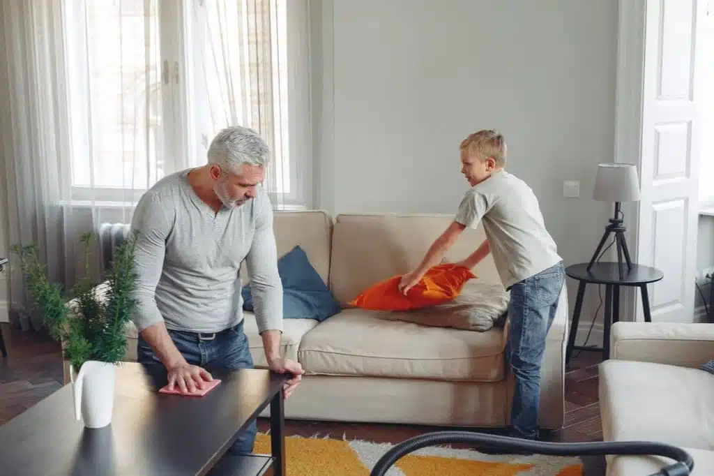 Father and son doing house work in a living room