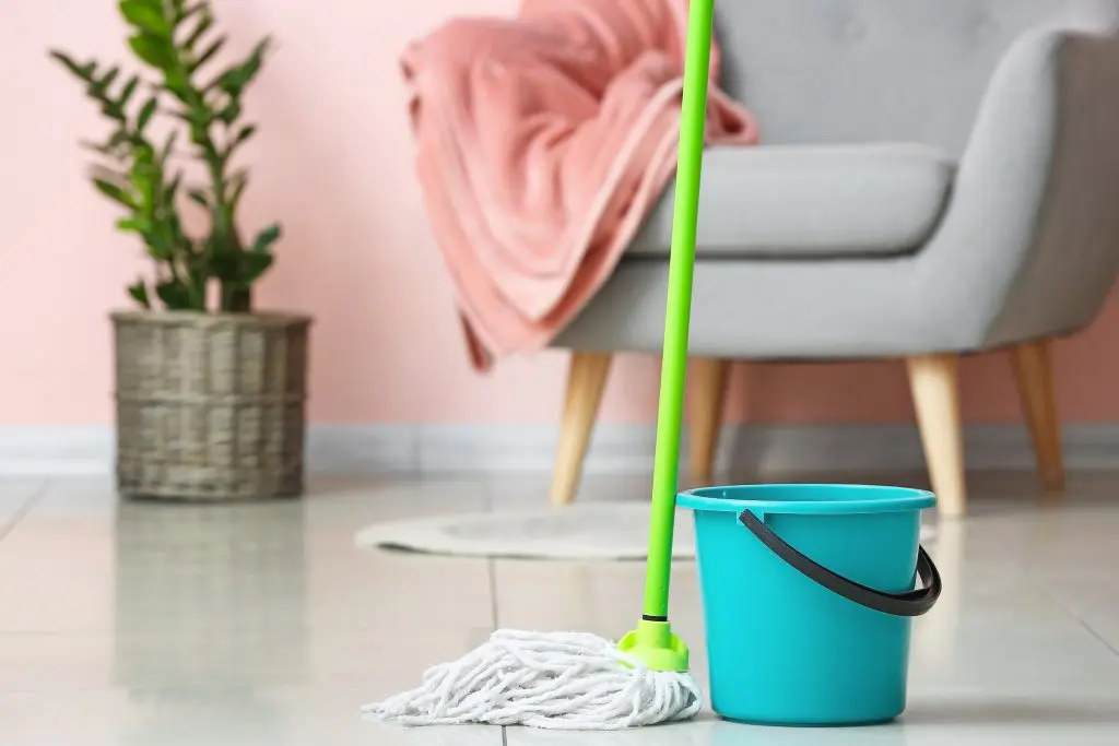 A mop and bucket with a chair in the background.