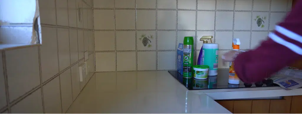 a kitchen with cleaning chemicals on the induction cooker with a lady cleaning it