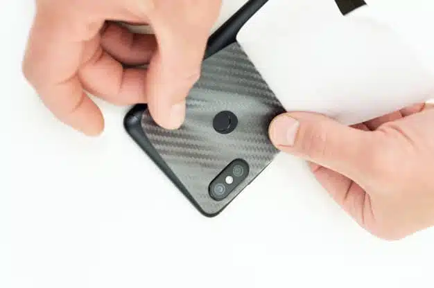 man is glueing protective carbon film smartphone