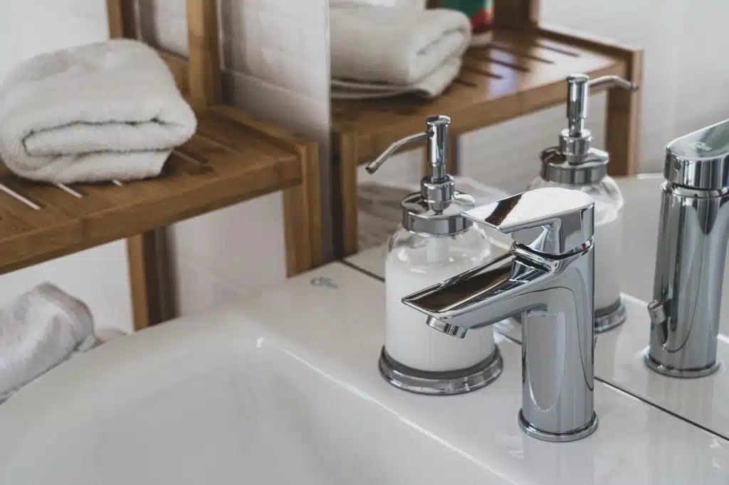 Stainless steel bathroom faucet in an all white bathroom
