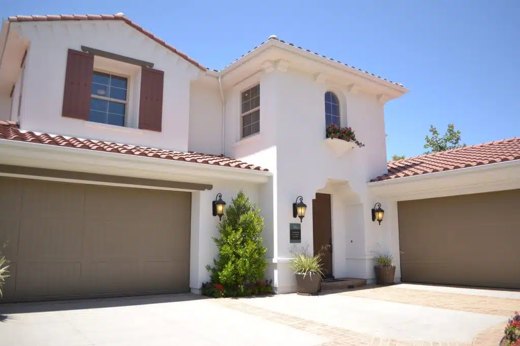 White concrete 3 story house with brown painted garage doors