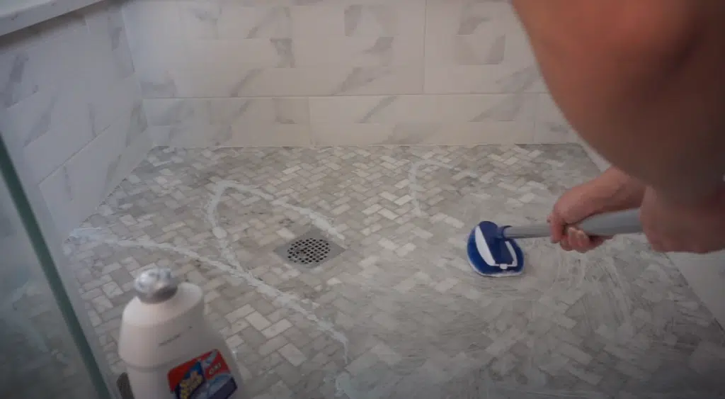 A person cleaning mould from a shower floor