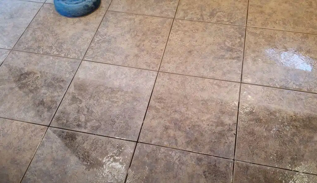 Dirty natural stone tiled floor being cleaned