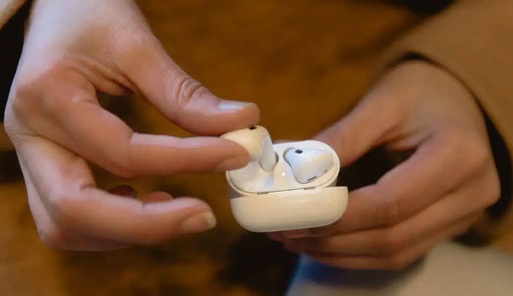 person holding apple airpods and airpods case