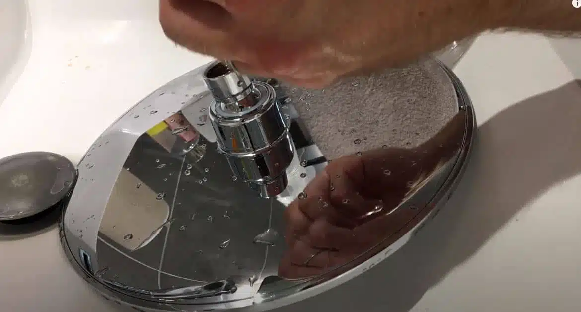 cleaning a rainfall shower head in a white basin