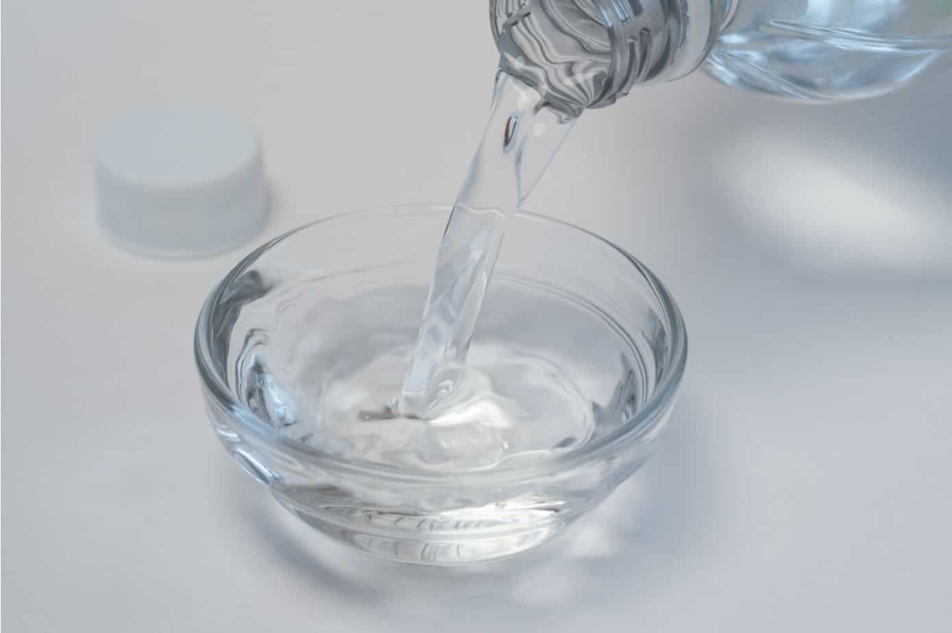 pouring white vinegar into a large see-through bowl