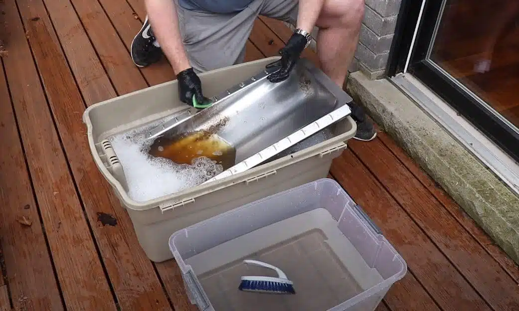 washing barbeque grill components in a large plastic tub