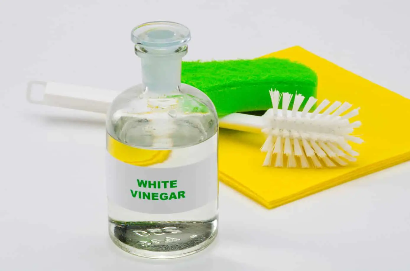 bottle of white vinegar sitting on a table with other cleaning equipment