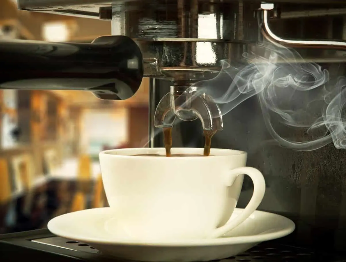 coffee maker brewing fresh coffee in a white tea cup