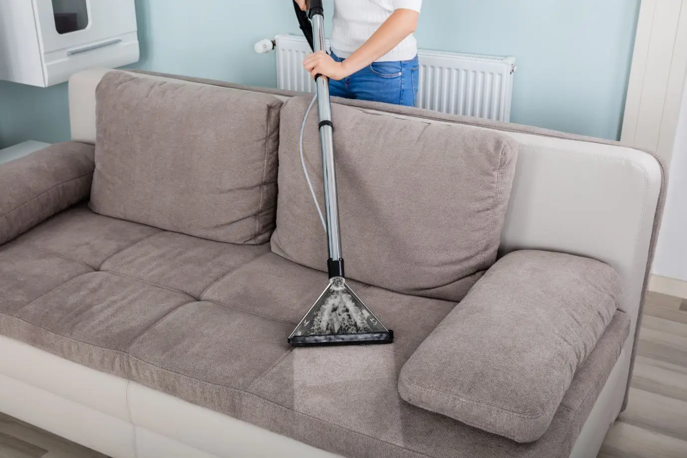 man cleaning upholstered brown 2 seater couch