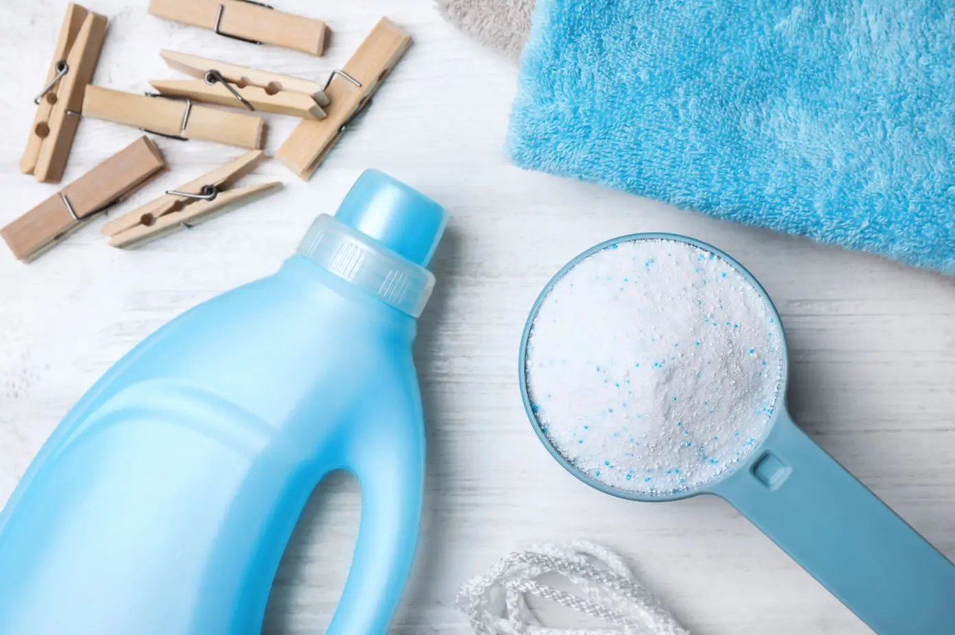 blue laundry detergent, cloths and pegs on a white table