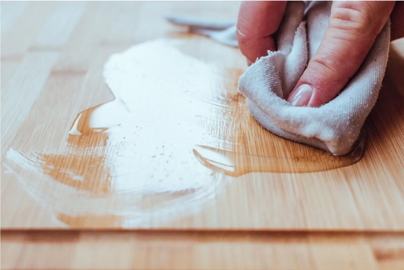 man applying finish with a white rag to wooden tabletop