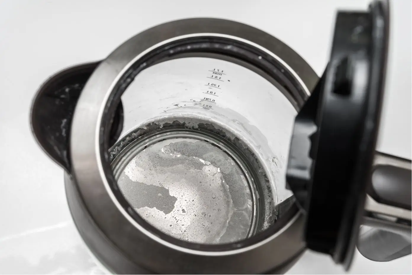 see through black and silver kettle with heavy limescale build up
