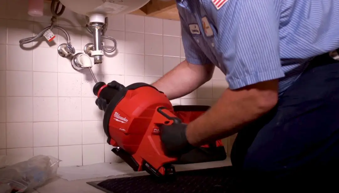 plumber using mechanical drain snake to unblock drain