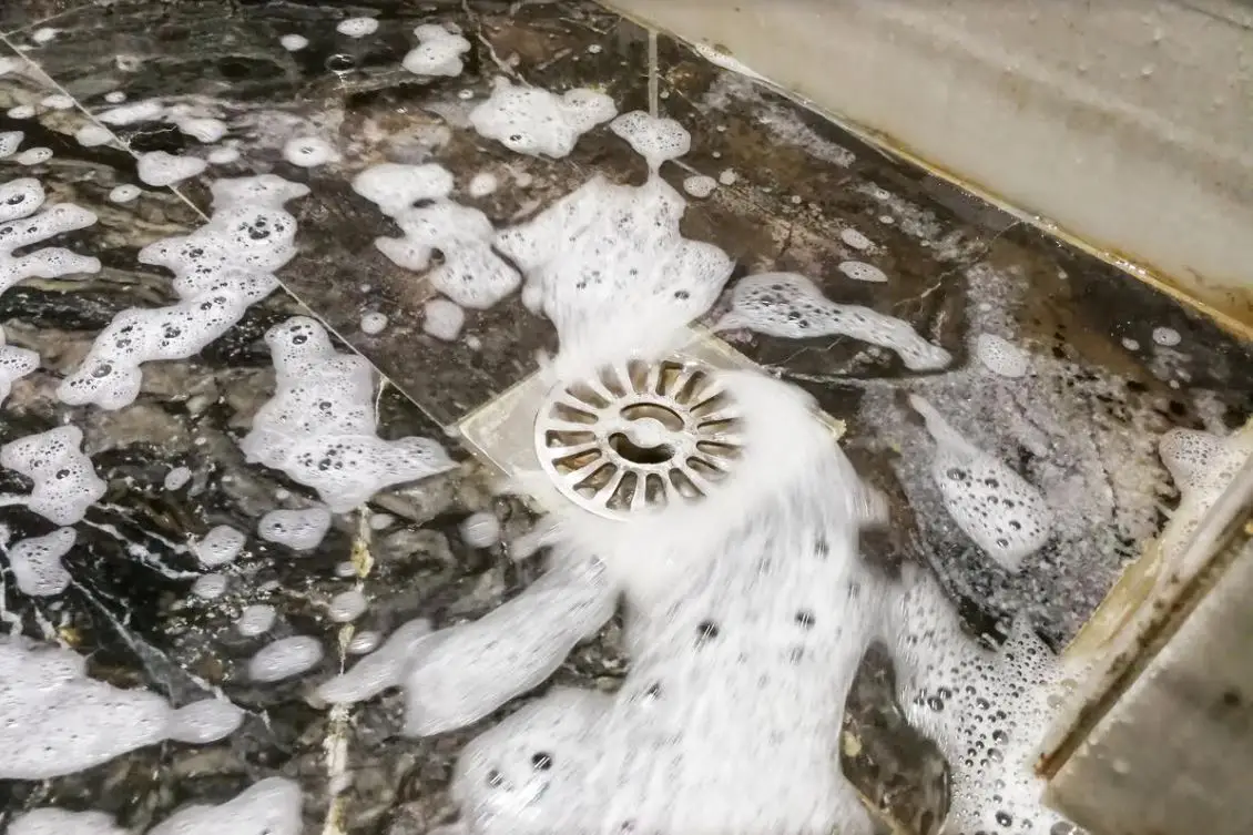 top view of soapy water running into a dirty shower drain