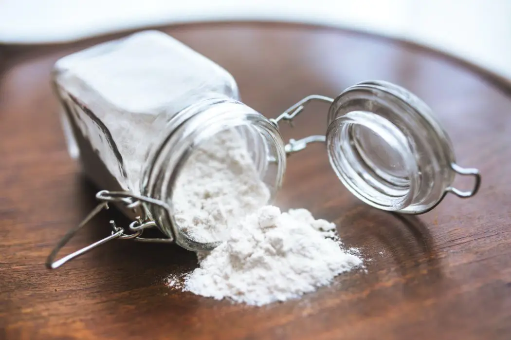 a jar of baking soda tipped over on a wooden countertop