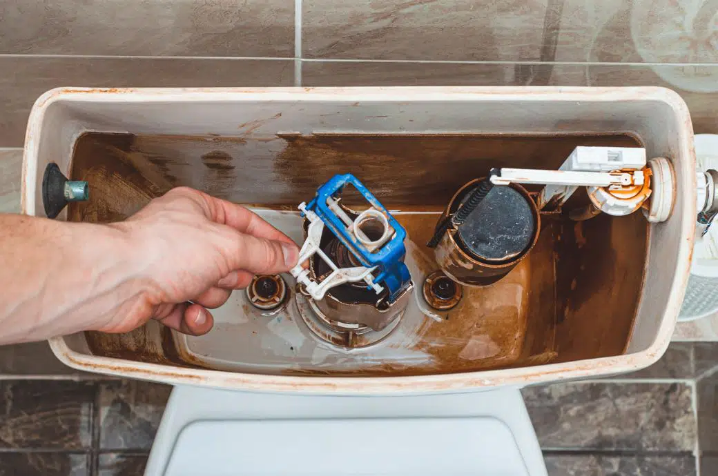 man draining water from dirty toilet tank