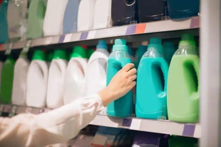 person selecting blue fabric softener off a store shelf