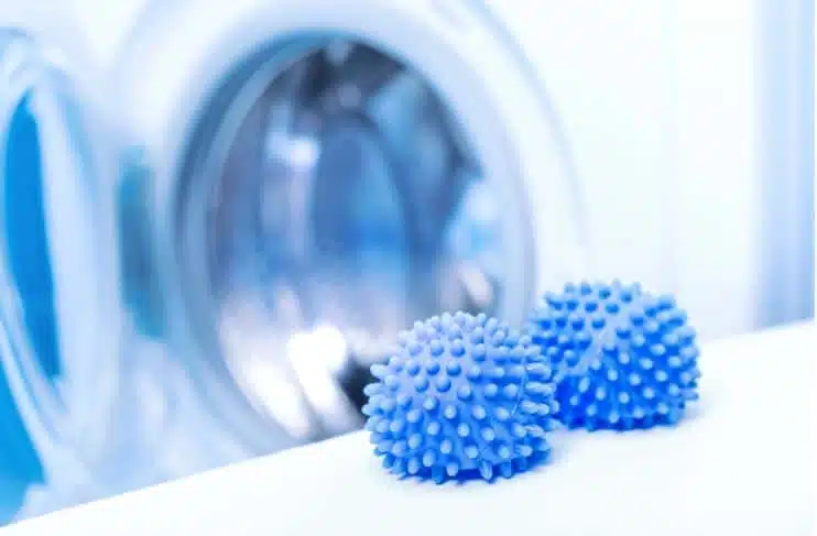 two blue dryer balls in front of a washing machine