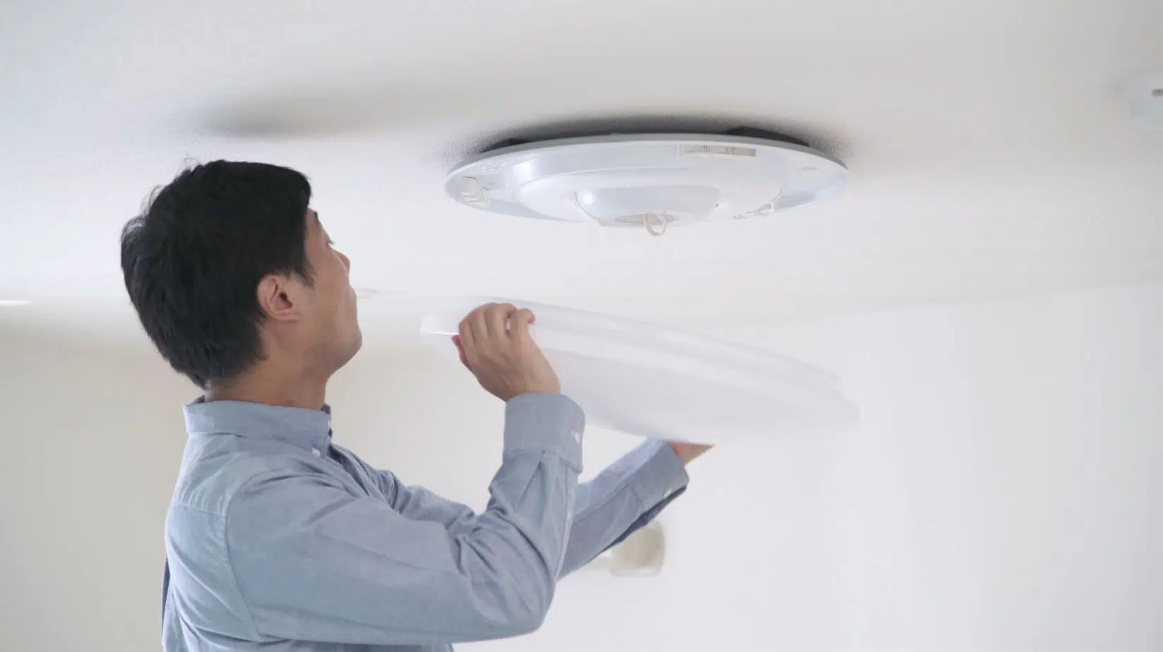 man in blue button up shirt removing cover from light fitting
