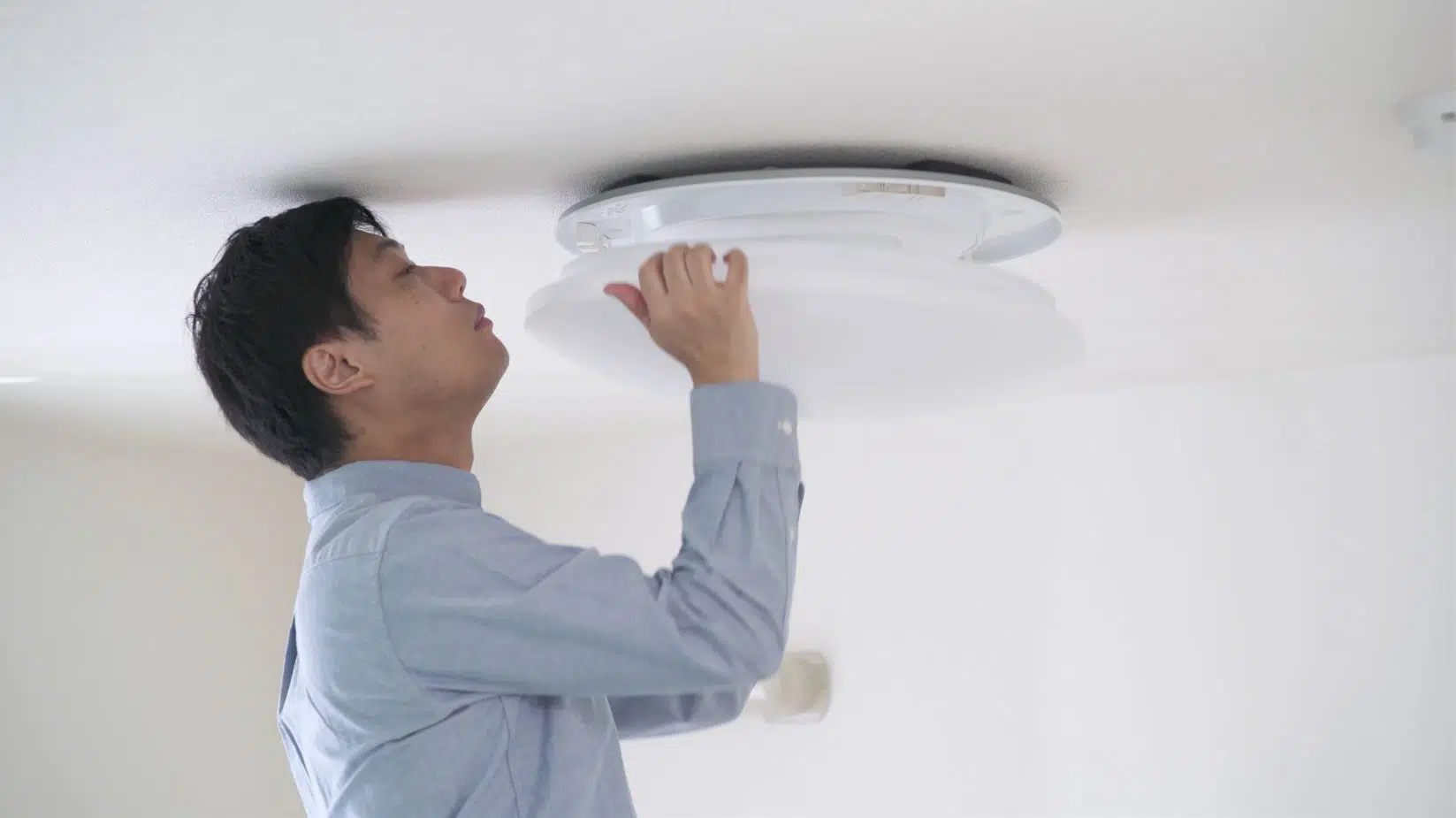 man in blue shirt placing cover on light fitting