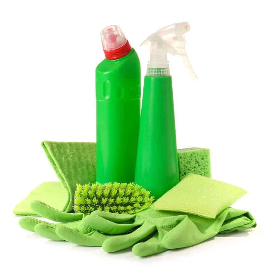 two green bottles of cleaning liquid on a table surrounded by clean microfibre cloths and green gloves