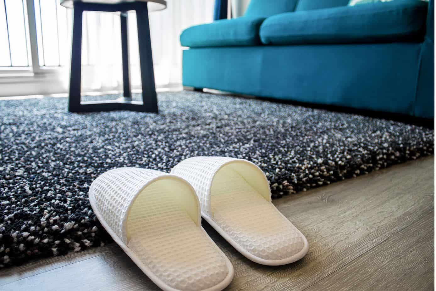 house slippers on a fluffy rug next to a blue upholstered couch