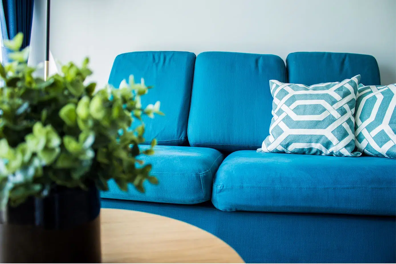 living room with upholstered three seater blue couch and two blue cushions