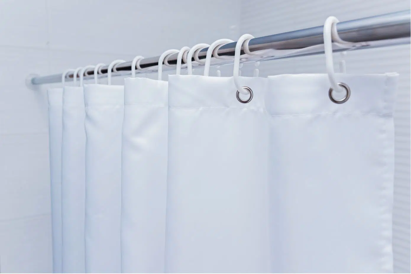 white hanging shower curtain on a steel rod