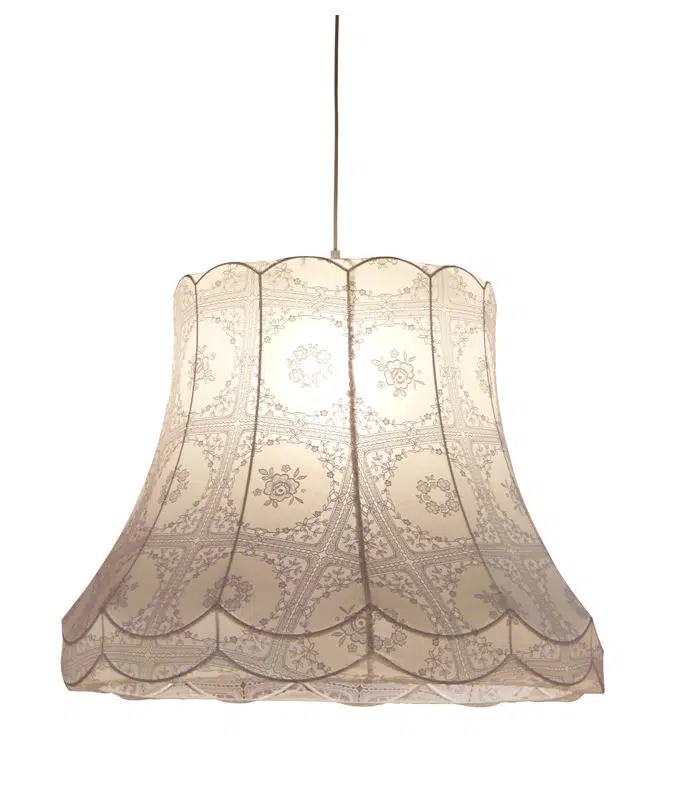 light brown antique fabric lampshade covering light bulb on a white background