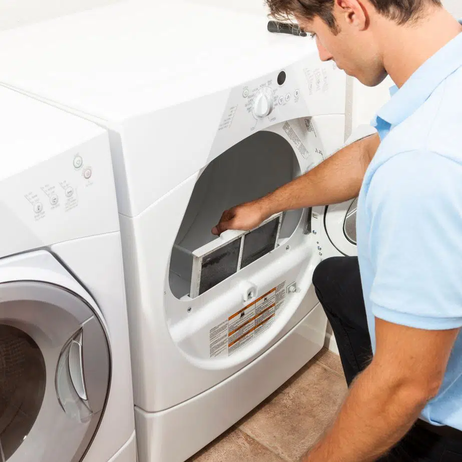 man in blue shirt cleaning lint trap in a front load dryer