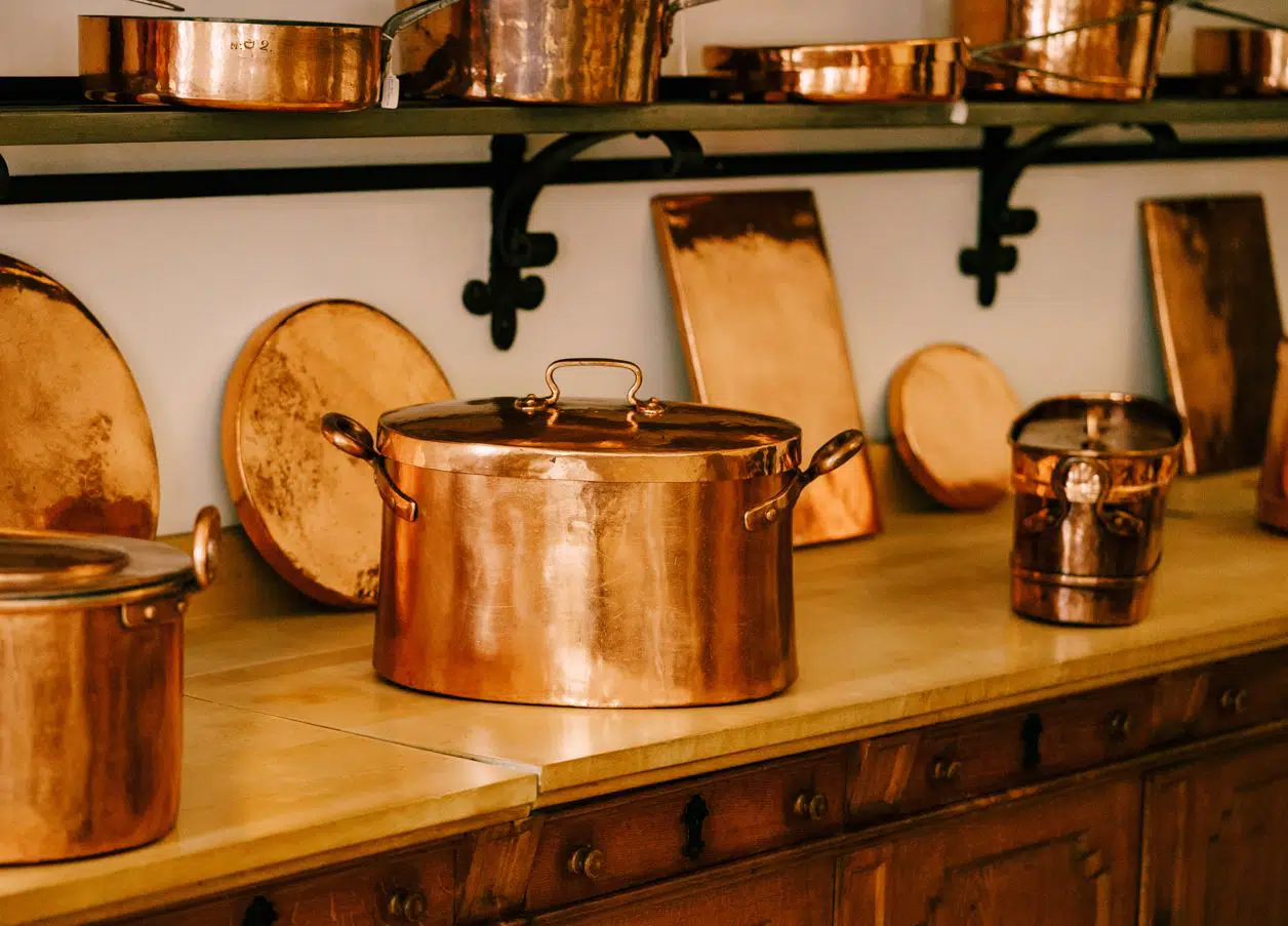 three polished copper pots on a wooden table