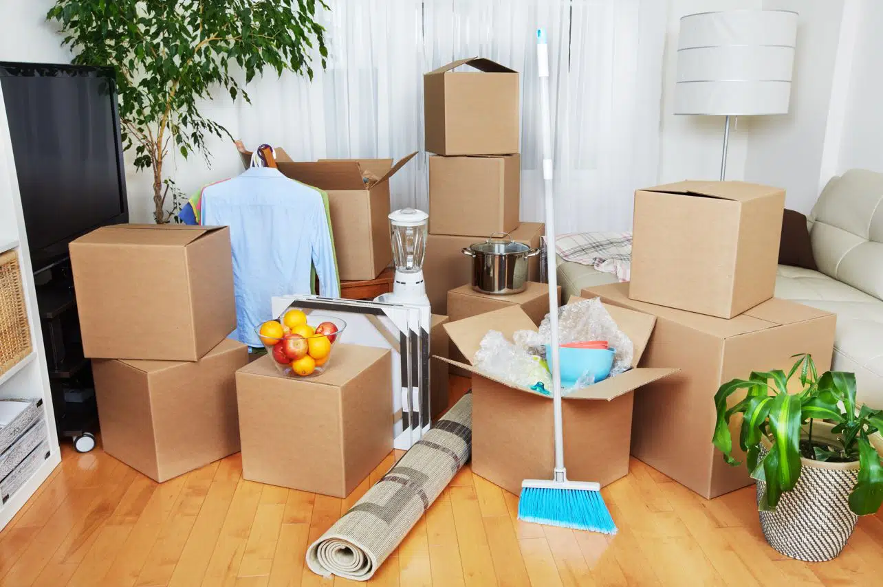 moving boxes on a wooden floor in a large living room with other assorted items packed together